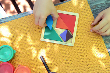 Tangram logic toy, little boy hands assemble the puzzle