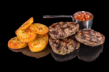 Delicious beef meatballs garnished with boiled potatoes and tomatoes sauce,  with reflection, isolated on black background