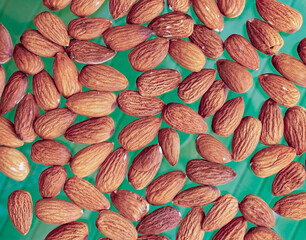 Dried almond nuts close up top view on a green background.