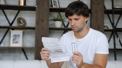 Man with medicine and pills. Ill man looking at medication explanation before taking prescription drugs.