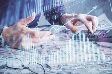 Plakat Double exposure of man's hands holding and using a digital device and forex graph drawing. Financial market concept.