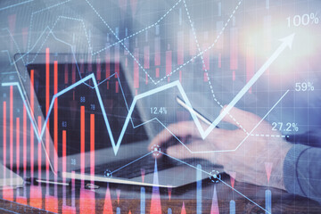 Double exposure of man's hands holding and using a digital device and forex graph drawing. Financial market concept.