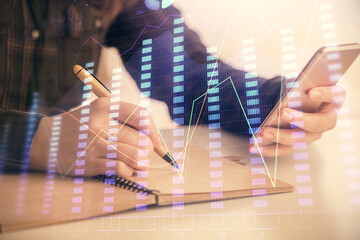Double exposure of forex graph sketch hologram and woman holding and using a mobile device. Stock market concept.