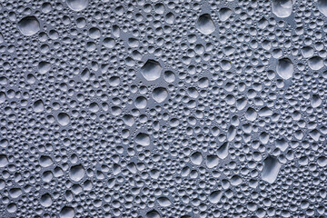 Drops of water after the rain on a glass panel with the sky above