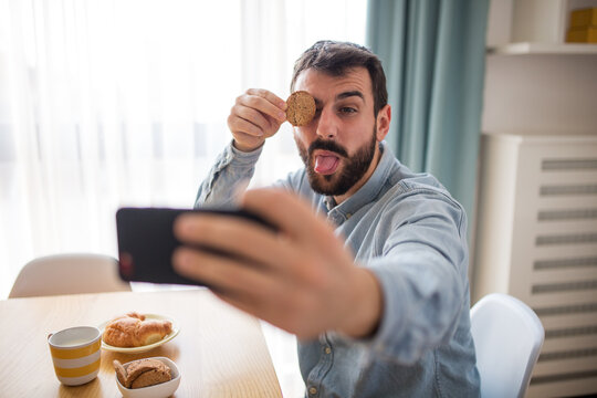 Funny young man take selfie at breakfast table