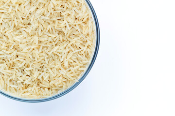 Basmati rice groats in a glass bowl on a white background. Dry basmati rice background. Basmati rice texture. A product of proper nutrition. Basmati rice grain background texture.Vegetarian food.