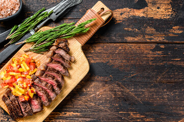 Grilled ramp cap steak on a cutting board. Dark wooden background. Top view.  Copy space