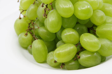 Green grapes on a white plate. Closeup