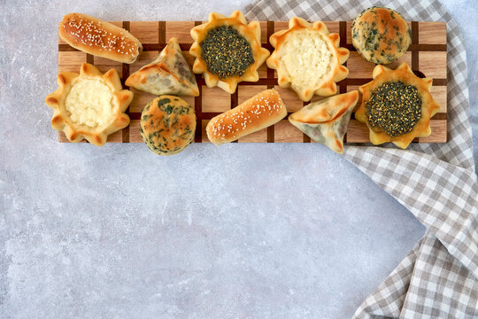 Pastries, fatayer or samosa, manaqeesh with zaatar and white cheese on wooden board
