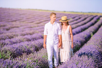 Family in lavender flowers field at sunset in white dress and hat