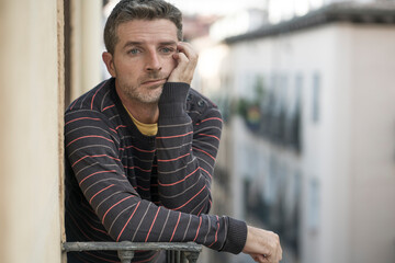 urban lifestyle emotional portrait of 40s handsome man sad and depressed at home balcony leaning upset feeling worried suffering depression problem looking to city street