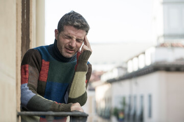 urban lifestyle emotional portrait of young attractive and depressed man at home balcony leaning upset feeling desperate suffering depression problem looking at city street