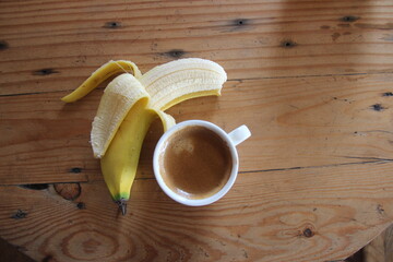 fresh bananas and warm coffee on a wooden table. a display of healthy food and drink