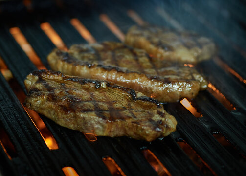 Grilled pica&ntilde;a meat cut with fire and smoke with dark background