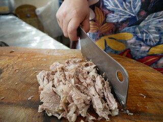 Hand cutting pork shop with knife on wooden 