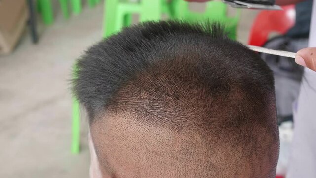 Slow motion of short haircuts for elementary school male students and male high school students in Thailand by using a hair clipper to cut hair with a comb in barber shop.