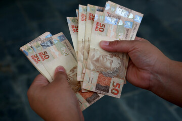 salvador, bahia / brazil - february 25, 2015: hands hold fifty reais (R $ 50.00) bills in the city...