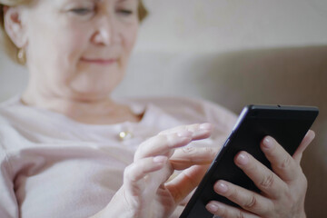 Beautiful middle age woman in soft focus working from home, using her tablet computer