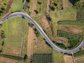 Aerial view top down from above on the country road in mountain range agriculture fields between...