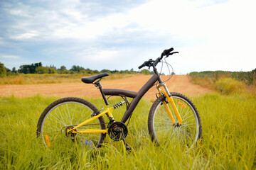 Fototapeta na wymiar A yellow mountain bike stands in a field. Travel, outdoor activities