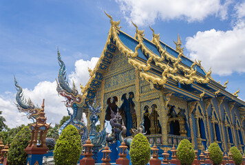 Naklejka premium Chiangrai, Thailand - June 7, 2020: Blue Yellow Thai Church and Serpent or Naga in Wat Rong Sues Ten Temple at Right View