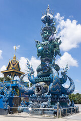 Fototapeta na wymiar Chiangrai, Thailand - June 7, 2020: Blue God Statue Hold Lotus and Ball on Blue Sky Background with Natural Light in Wat Rong Suea Ten Temple
