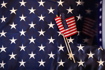 2 small USA flags lying over larger USA flag