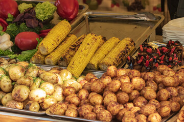 Culinary buffet with the presentation of healthy food - mushrooms, potatoes, sausages, peppers, spices, grilled vegetables. Food market, festival, event. The kitchen is outdoors. Street fair stand.