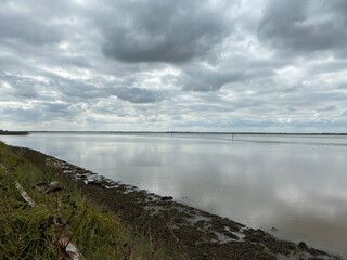 View of the broads National Park from the river bank in a cloudy day shoot taken against the sun with a dramatic sky and strong shadow.