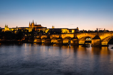 Fototapeta na wymiar Charles Bridge Illuminated in Prague at Dusk across River Vltava with Saint Vitus Cathedral and Prague Castle