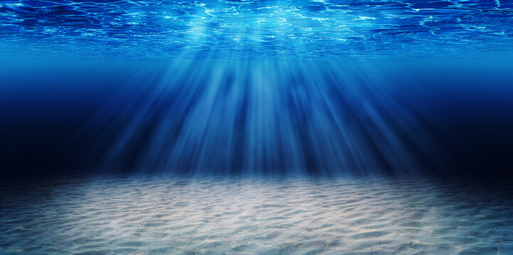 Abstract image of Tropical sand beach on the bottom of underwater dark blue deep ocean wide nature background with rays of sunlight.