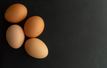 cuatro huevos café sobre un fondo color negro mate