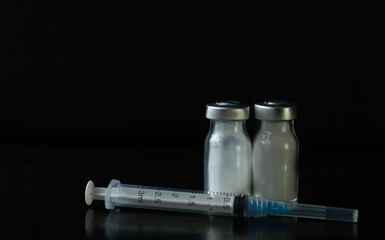 jeringas de tres mililitros con frascos de medicamento con polvo blanco en un fondo negro
