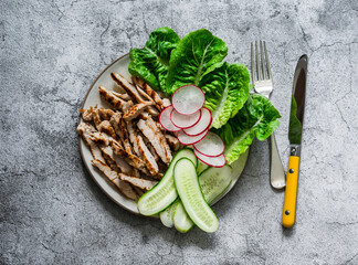 Grilled chicken, green romaine salad and fresh vegetables on a grey background, top view. Diet balanced food concept