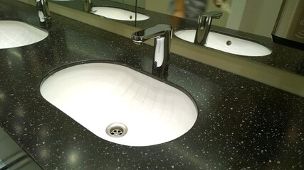 Bathroom sinks and touchless taps in public toilet and restroom. Modern faucet. Virus protection...