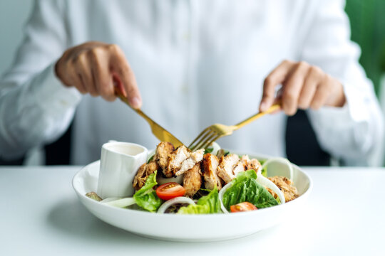 Closeup image of a woman eating chicken salad on table in the restaurant