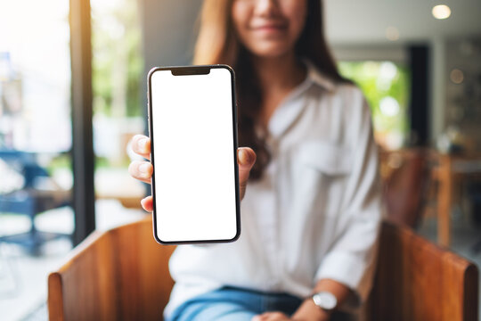 Mockup image of a woman holding and showing mobile phone with blank white screen