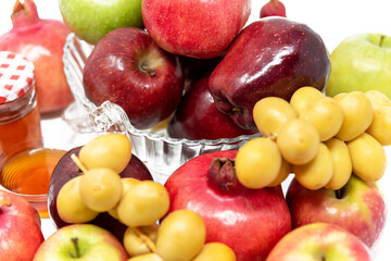 Rosh Hashanah, Jewish New Year, Traditional Symbols, Honey in a glass jar, Pomegranates, Dates, Red And Green Apples. Isolated On A White Background