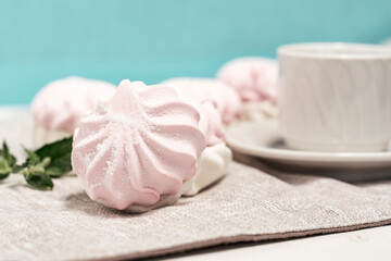 Fototapeta na wymiar delicate light marshmallows with a mint leaf and a cup of tea on a light background