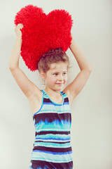 Little girl kid with red heart shape pillow.