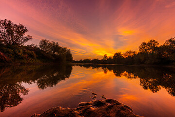 Wild, colorful sunset over tranquill river in a remote area in Europe