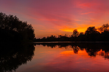 Wild, colorful sunset over tranquill river in a remote area in Europe