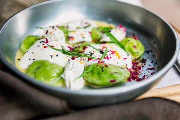 Ravioli with spinach and cheese on a plate on a table in a cafe. Close-up. Delicious Italian cuisine.