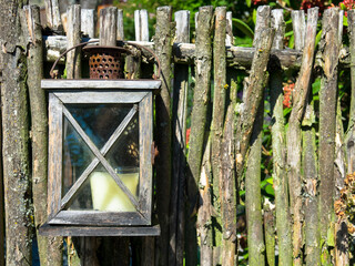 Rustic candle lantern hanging on wooden fence