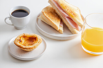 Typical Portuguese breakfast. Black coffee bica, sandwich mixto, pastel de nata (egg tart pastry) and orange juice.