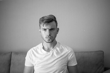 Black and White, Young white man wearing t-shirt standing over isolated green background skeptic and nervous, frowning upset because of problem. Negative person.