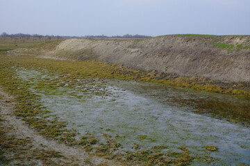 The exposed bottom of a dry pond. A shallow water body. A steep slope of the bank of an artificial pond.