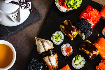 Sushi Set sashimi and sushi rolls served on stone slate