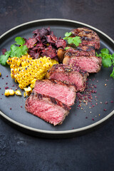 Barbecue dry aged wagyu roast beef steak with corn and vegetable chips offered as close-up on a modern design plate