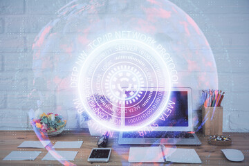 Computer on desktop in office with technology theme hologram. Double exposure. Tech concept.